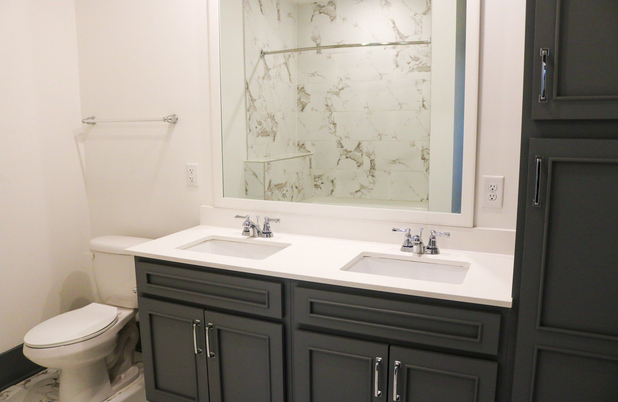 bathroom inside apartment showing toilet, double sinks, and cabinetry